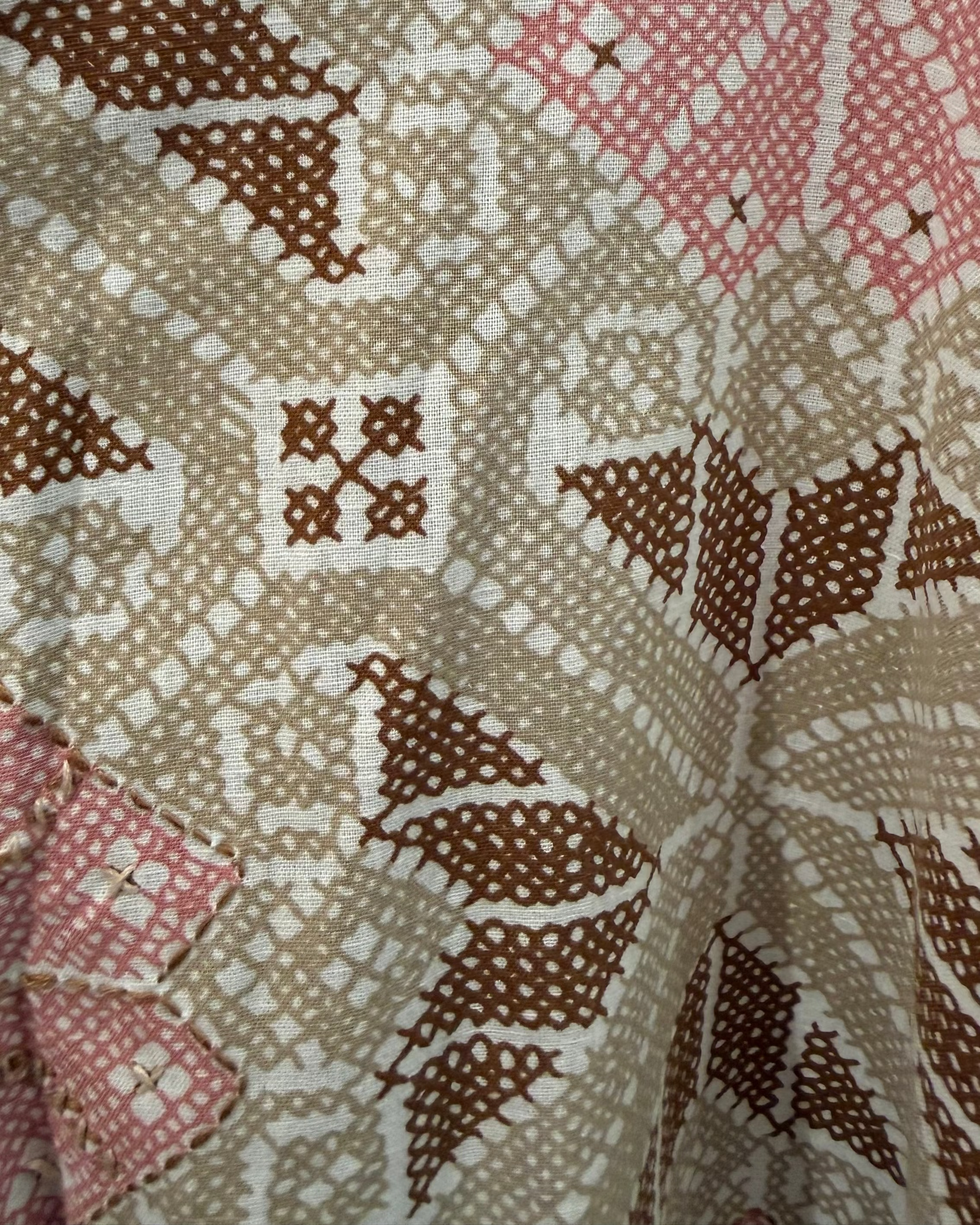 Close-up of a quilt with diamond pattern in brown, red, and beige.